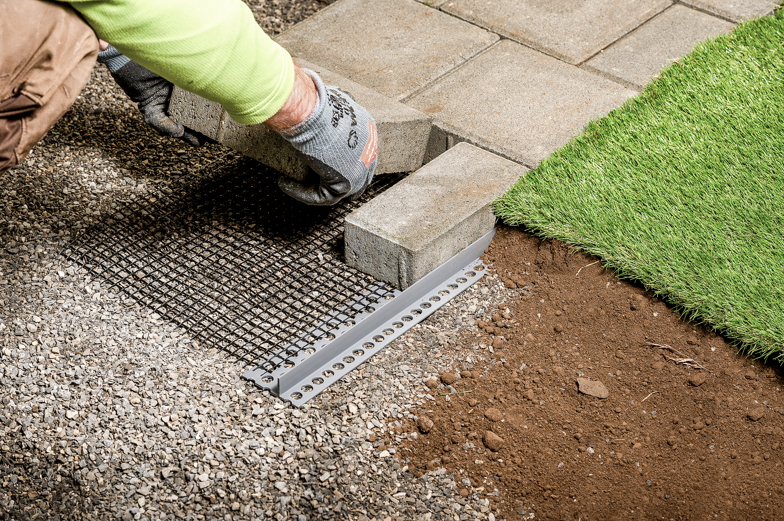 Gartenbauer beim Verlegen von Pflastersteinen mit steinfix Randabschlussprofil